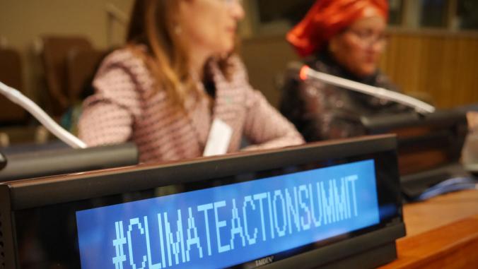 牌子上写着， “#ClimateActionSummit。”Chilean Minister of Environment Carolina Schmidt and U.N. Deputy Secretary-General Amina J. Mohammed pictured in background.