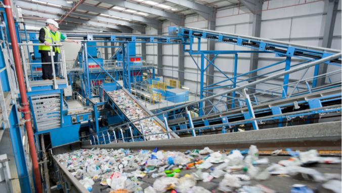 Wide shot of Businessman and worker talking on platform above conveyor belts in recycling plant