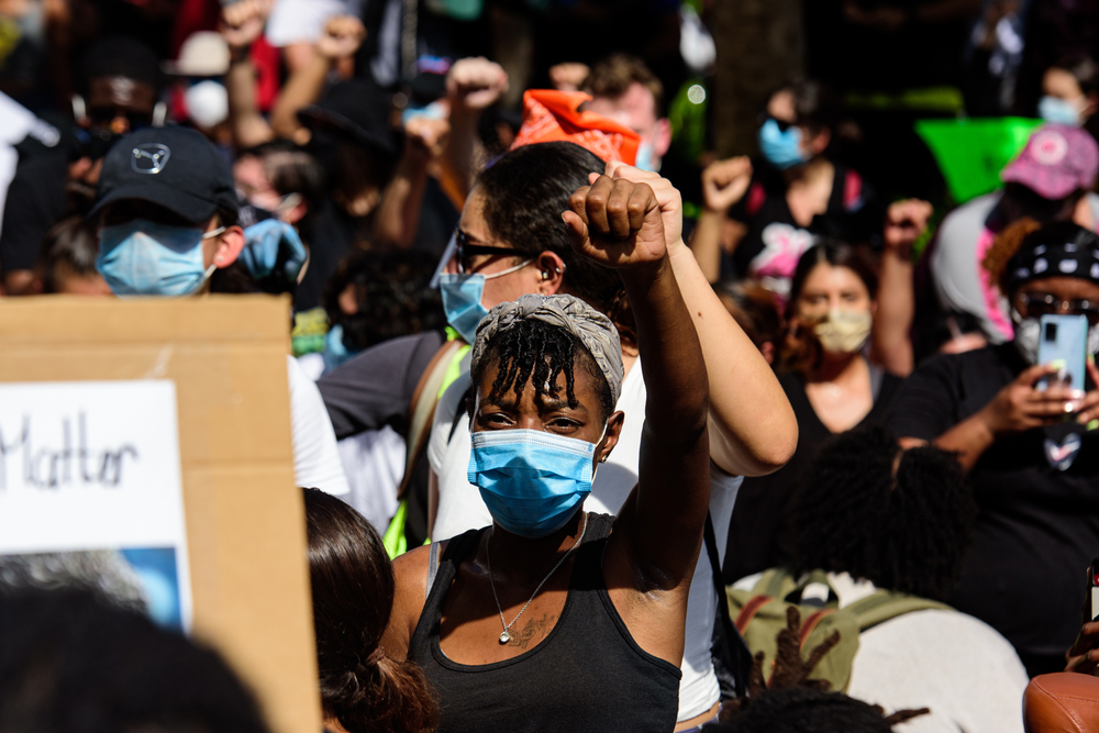黑人佩带的面具和领导一个小组示威者在一条路在街市迈阿密，佛罗里达。