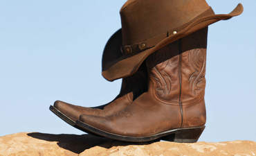 牛仔帽和靴子放在干燥的土地上