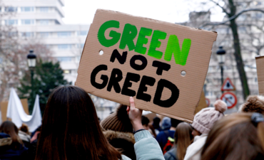 气候游行的标志上写着绿色而不是贪婪