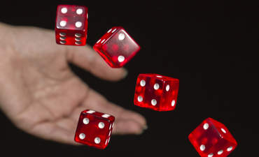 一位女手滚动几个红色骰子。