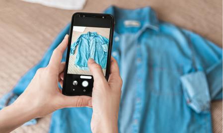 Hands of a person taking photo of denim shirt on smartphone