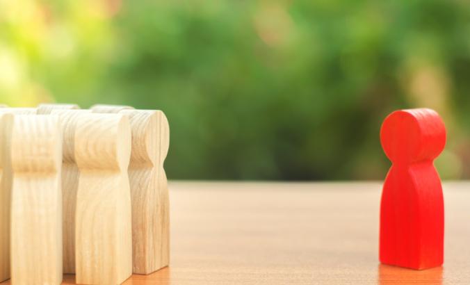 Wooden figurines represent one person outside the group