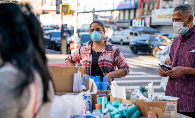 2019冠状病毒病大流行期间，戴口罩的人在纽约市曼哈顿华盛顿高地的一个街头摊位上销售美容产品。