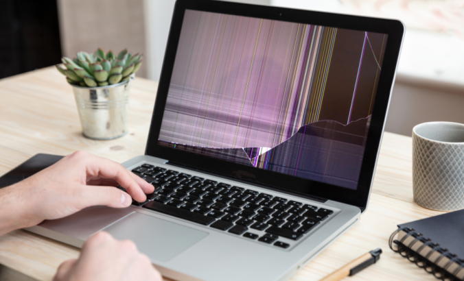 Person working with a computer with damaged screen, office business background.