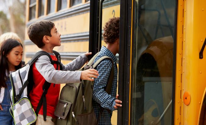 Elementary school kids climbing on to a school bus