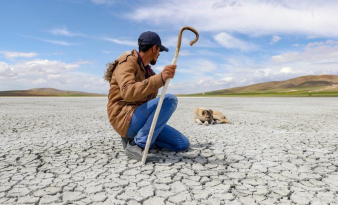 Man kneels in desert with dog