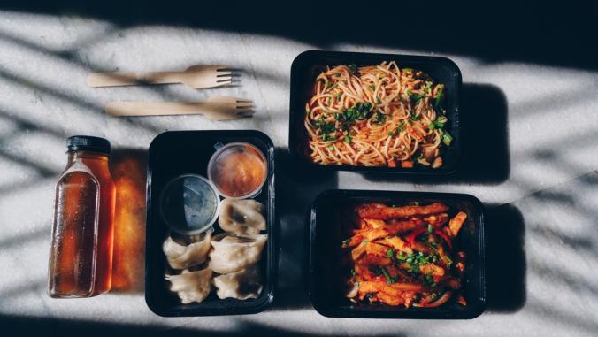 Chinese food in containers against white background in shadow