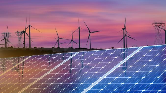 Solar panels and windmills at sunset